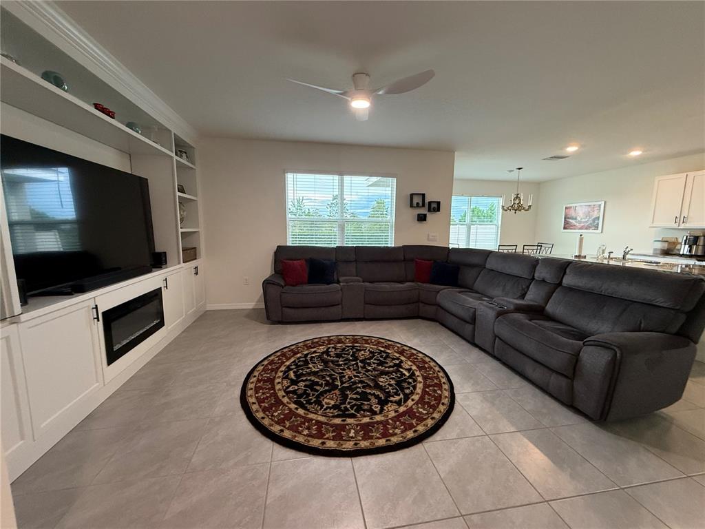 A living room features a large sectional sofa, a built-in media center, and tile flooring — 3521 MAPLE GROVE WAY, PLANT CITY, FL
