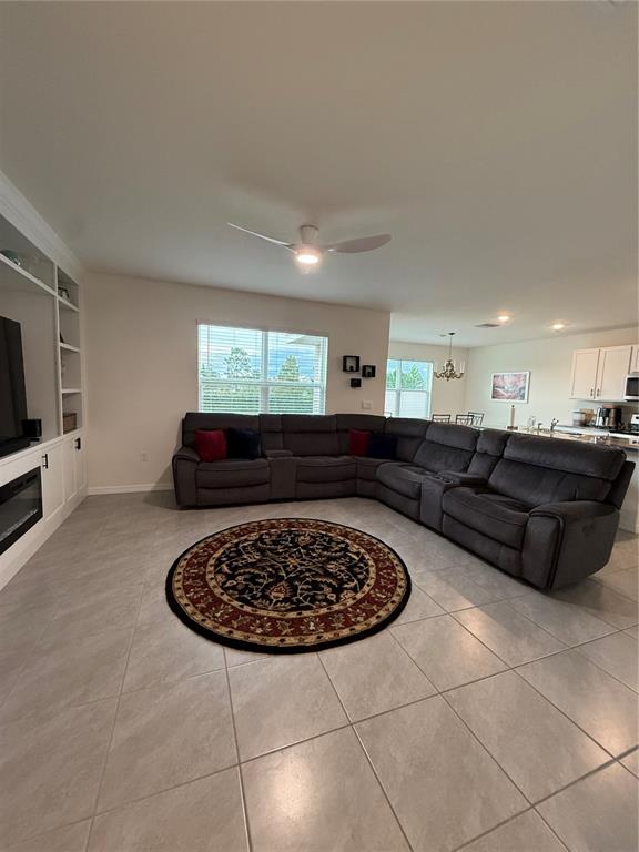 A living room features a large gray sectional sofa, a circular rug, and tile flooring — 3521 MAPLE GROVE WAY, PLANT CITY, FL