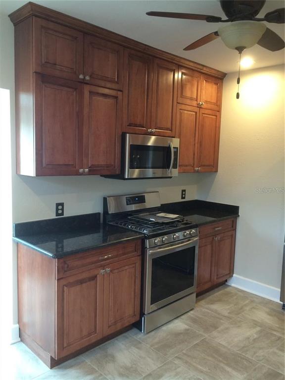 A kitchen features wood cabinets, stainless steel appliances, and dark countertops over tile flooring — 2926 2ND AVENUE N Apt B, ST PETERSBURG, FL