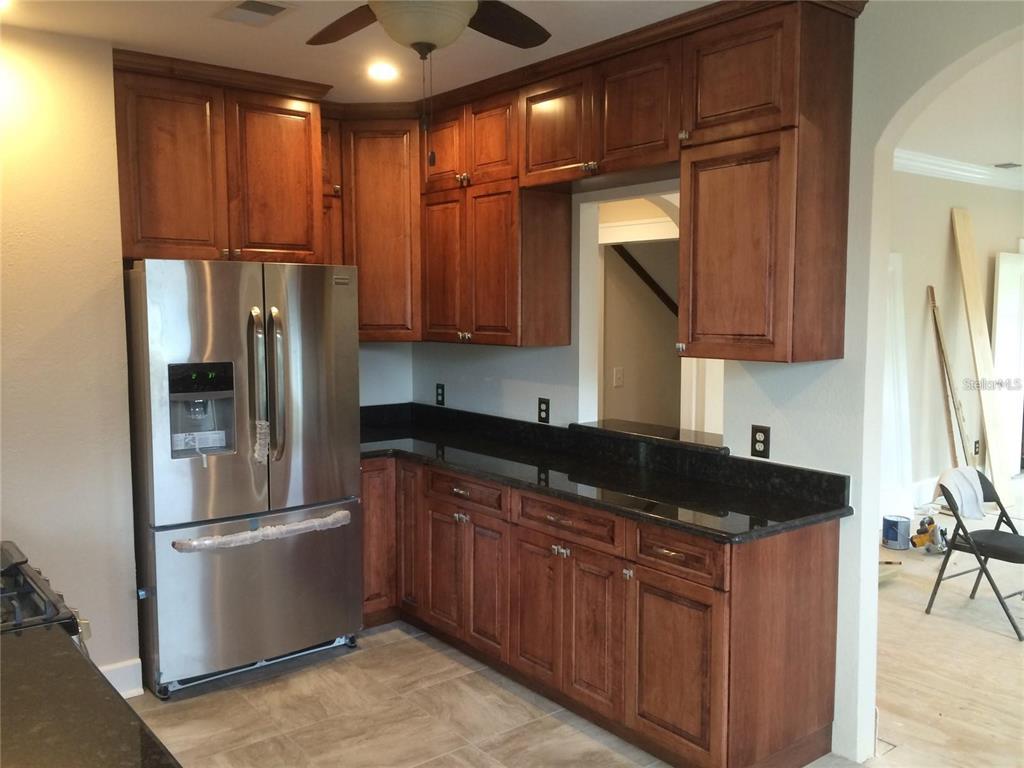 A kitchen features dark wood cabinets, black granite countertops, stainless steel appliances, and tile flooring — 2926 2ND AVENUE N Apt B, ST PETERSBURG, FL