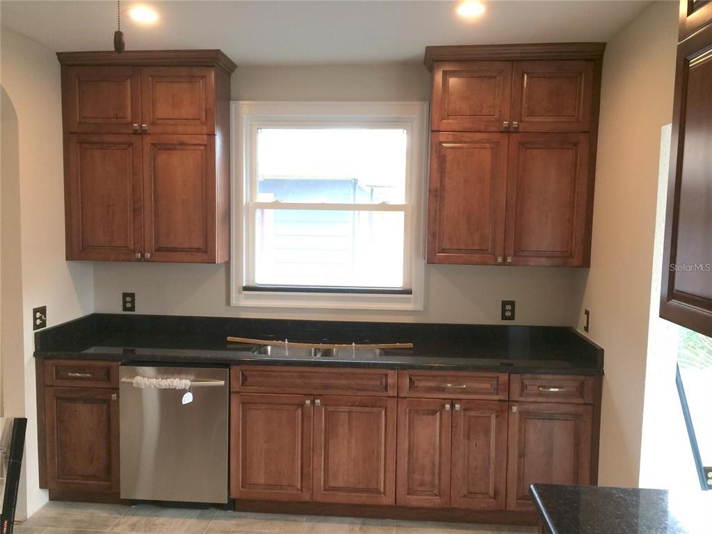 A kitchen features wooden cabinets, a black countertop, a stainless steel dishwasher, and a window — 2926 2ND AVENUE N Apt B, ST PETERSBURG, FL