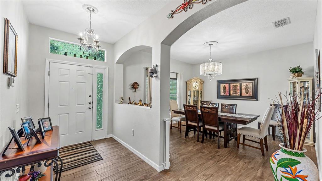 An entryway with a wood-look tile floor leads into a dining room with a chandelier — 1053 KRENSON WOODS ROAD, LAKELAND, FL