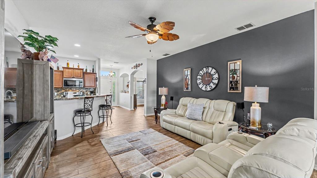 A living room with a gray accent wall, white leather sofas, and an open kitchen — 1053 KRENSON WOODS ROAD, LAKELAND, FL