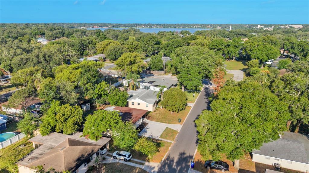 An aerial view shows a residential neighborhood with houses, trees, and a distant lake — 1615 SKINNER STREET, LAKELAND, FL