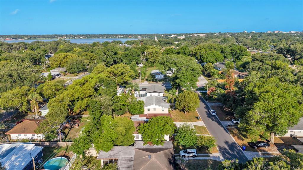 An aerial view shows a residential neighborhood with houses, lush trees, and a swimming pool — 1615 SKINNER STREET, LAKELAND, FL