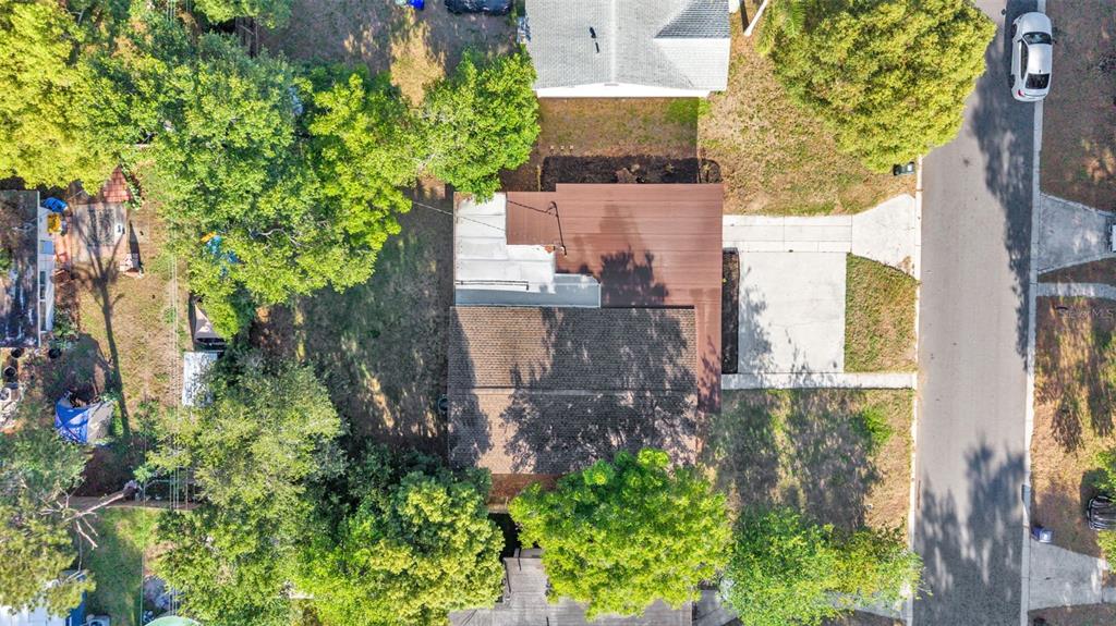 An aerial view shows a house with a brown roof, a driveway, and surrounding trees — 1615 SKINNER STREET, LAKELAND, FL