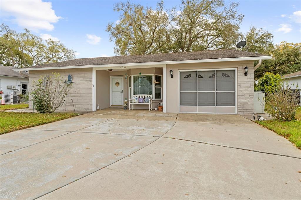 A single-story house exterior features a concrete driveway, a covered porch, and a garage door — 8030 GLENEAGLE DRIVE, PORT RICHEY, FL
