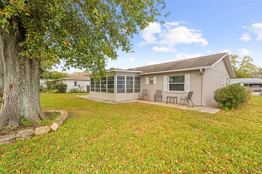 The exterior of a beige house features a screened-in porch and a large oak tree — 8030 GLENEAGLE DRIVE, PORT RICHEY, FL