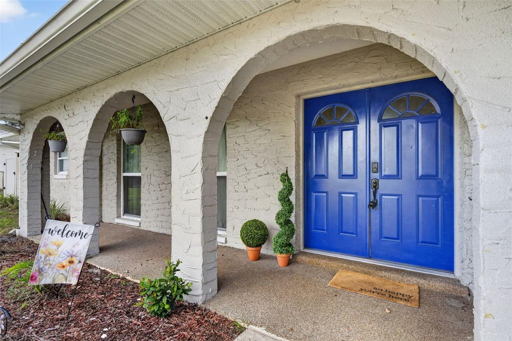 A front porch with arched columns leads to a pair of bright blue double doors — 112 ROOSEVELT PLACE, MAITLAND, FL
