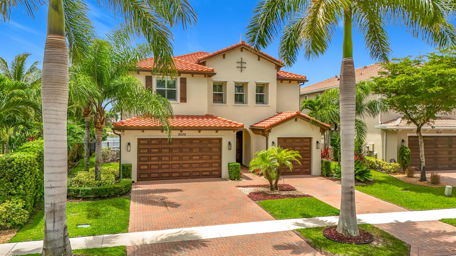 A two-story stucco house with a red tile roof and two wooden garage doors — 9508 Phipps Lane, Wellington FL 33414, WELLINGTON, FL