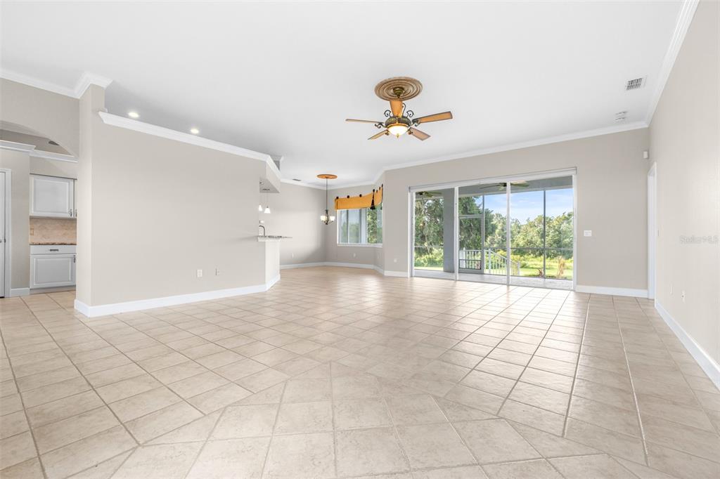 A spacious living area with beige tile flooring, a ceiling fan, and sliding glass patio doors — 2636 HUNTINGTON HILLS DRIVE, LAKELAND, FL