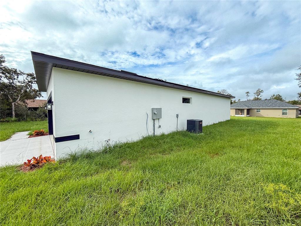 A side view of a white house exterior with a garage and an HVAC unit — 15716 SW 46TH AVENUE ROAD, OCALA, FL