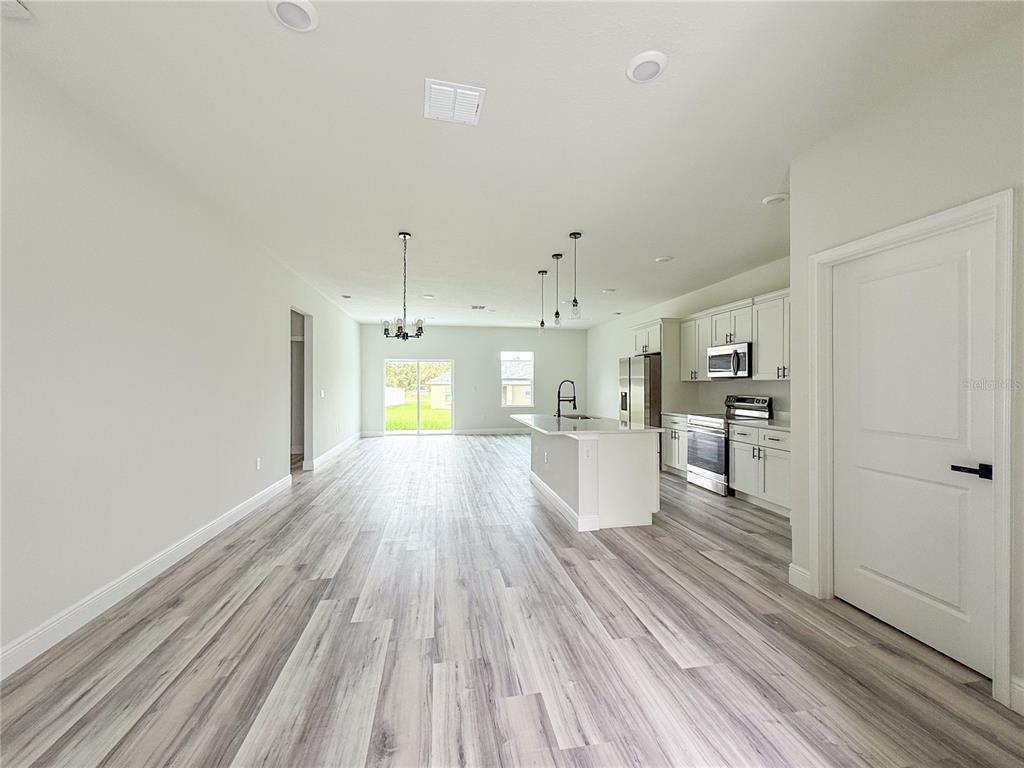 An open-concept kitchen and living area features light wood-look flooring and white cabinetry — 15716 SW 46TH AVENUE ROAD, OCALA, FL
