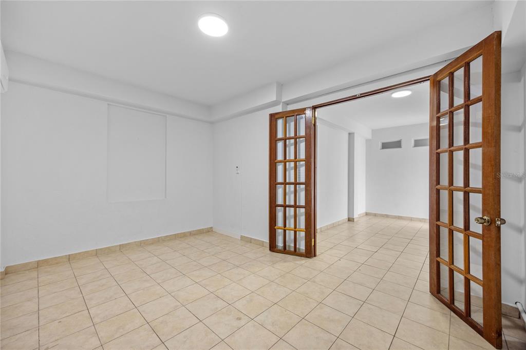 An empty room with beige tile floors and wooden French doors leading to another space — CAPARRA HEIGHTS J-42 ESCORIAL AVENUE UNIT 603, SAN JUAN, PR