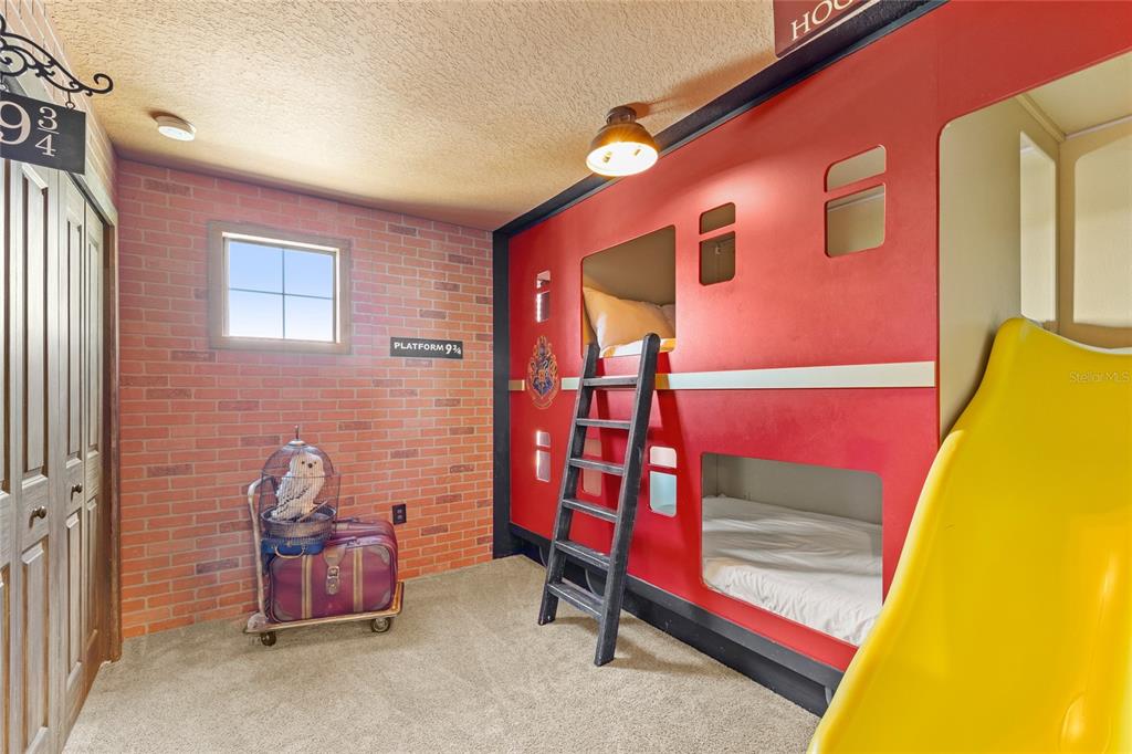 A Harry Potter-themed bedroom features a train-shaped bunk bed, a slide, and brick-patterned wallpaper — 1568 FLANGE DRIVE, DAVENPORT, FL