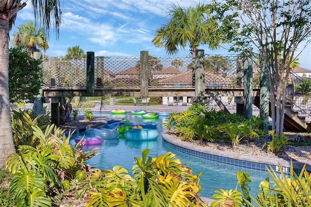 A wooden footbridge crosses over a lazy river pool surrounded by tropical landscaping — 1568 FLANGE DRIVE, DAVENPORT, FL