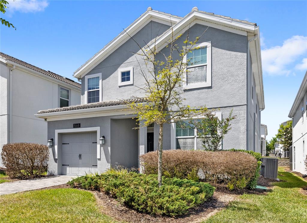 A two-story gray stucco house features a single-car garage and a small front yard — 1568 FLANGE DRIVE, DAVENPORT, FL