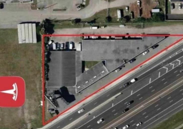 This aerial view shows a commercial building on a triangular lot next to a highway — 10300 US HIGHWAY 19 N, PINELLAS PARK, FL