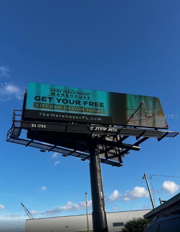 A large digital billboard displays an advertisement for The Home Improvement Warehouse against a blue sky — 10300 US HIGHWAY 19 N, PINELLAS PARK, FL