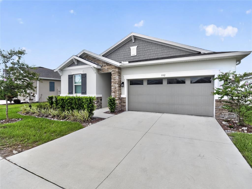 A single-story house features a gray garage, stone accents, and a landscaped front yard — 992 GRIFFON AVENUE, LAKE ALFRED, FL