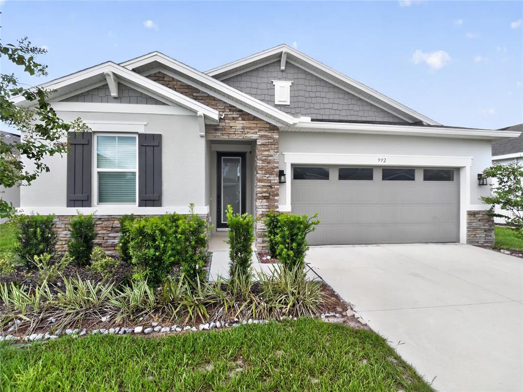 A single-story house features a stone facade, gray siding, a garage, and a front lawn — 992 GRIFFON AVENUE, LAKE ALFRED, FL