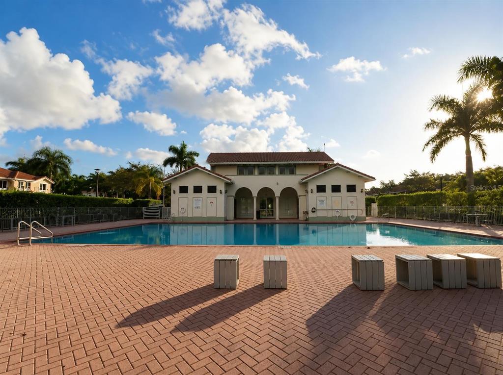 A swimming pool sits in front of a community building with a brick patio — 1452 SE 24TH AVE, HOMESTEAD, FL