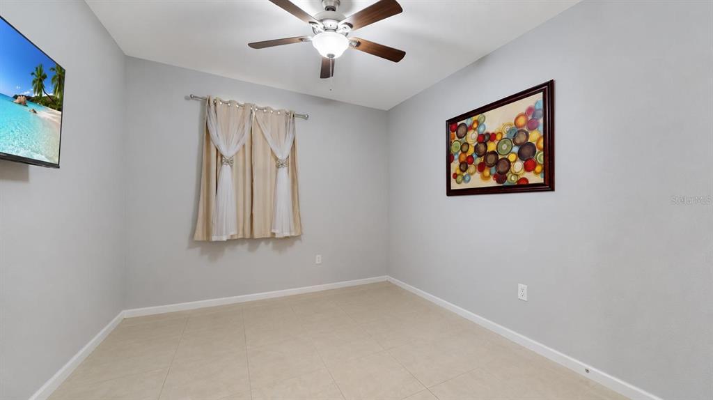 A bedroom with light gray walls, tile flooring, a ceiling fan, and a window — 1452 SE 24TH AVE, HOMESTEAD, FL