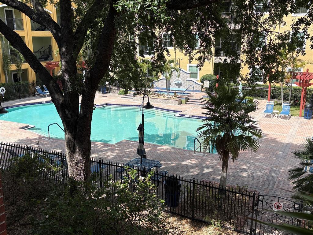 An outdoor swimming pool with a fountain and lounge chairs surrounded by apartment buildings — 1810 E PALM AVENUE UNIT 4201, TAMPA, FL