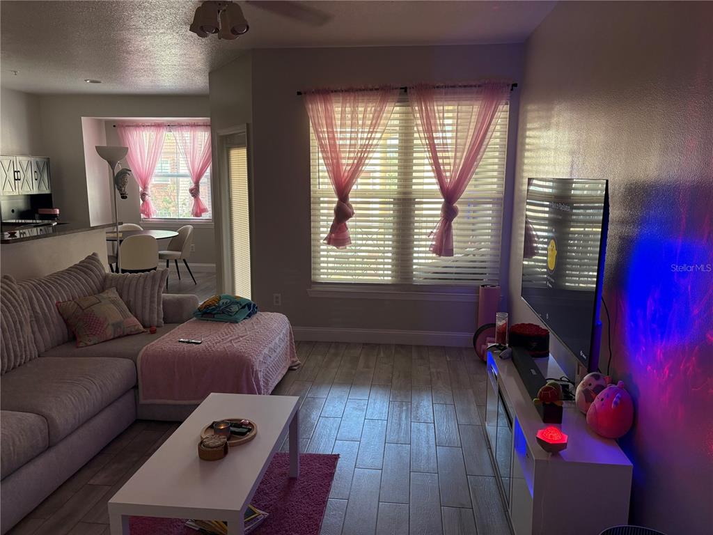 A living room features a sectional sofa, a white coffee table, and a wall-mounted television — 1810 E PALM AVENUE UNIT 4201, TAMPA, FL