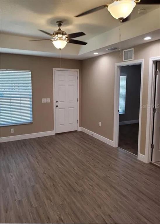 A room with wood-look flooring, two ceiling fans, a white door, and a doorway — 9445 N MANASHEE DRIVE, CITRUS SPRINGS, FL
