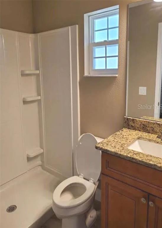 A bathroom features a walk-in shower, a toilet, and a vanity with a granite countertop — 9445 N MANASHEE DRIVE, CITRUS SPRINGS, FL