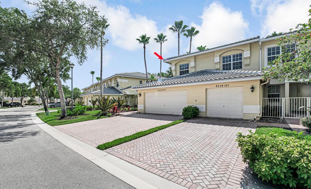 A two-story townhouse exterior features a paved driveway, two garage doors, and palm trees — 9778 Bowline Drive # 201, West Palm Beach FL 33411, WEST PALM BEACH, FL