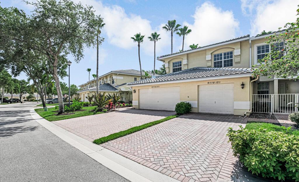 A two-story residential building with two garage doors and a paved driveway under a sky — 9778 Bowline Drive # 201, West Palm Beach FL 33411, WEST PALM BEACH, FL
