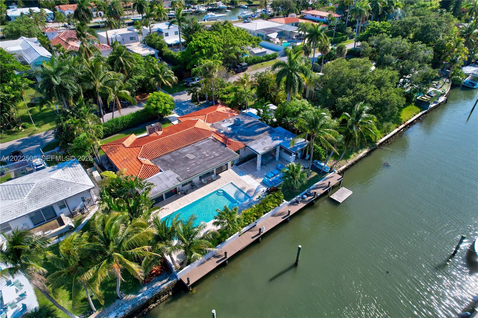An aerial view shows a waterfront house with a red-tiled roof, swimming pool, and dock — 1141 NE 90th St, Miami FL 33138, MIAMI, FL