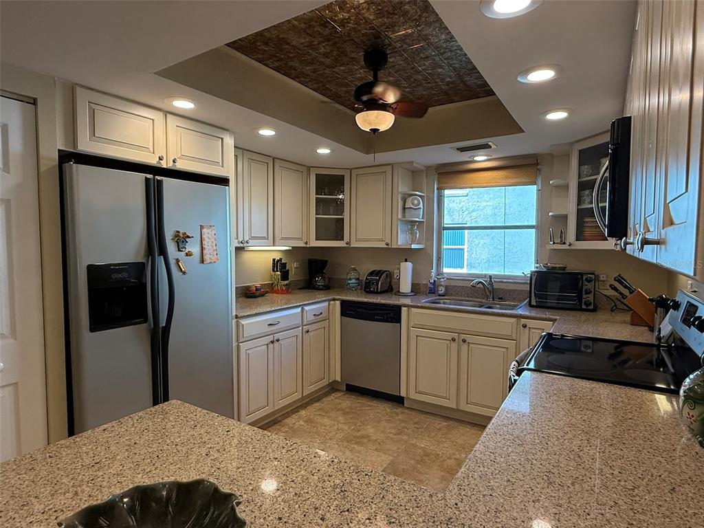 A kitchen features light-colored cabinetry, granite countertops, stainless steel appliances, and a textured ceiling inlay — 1250 S PINELLAS AVENUE UNIT 802, TARPON SPRINGS, FL