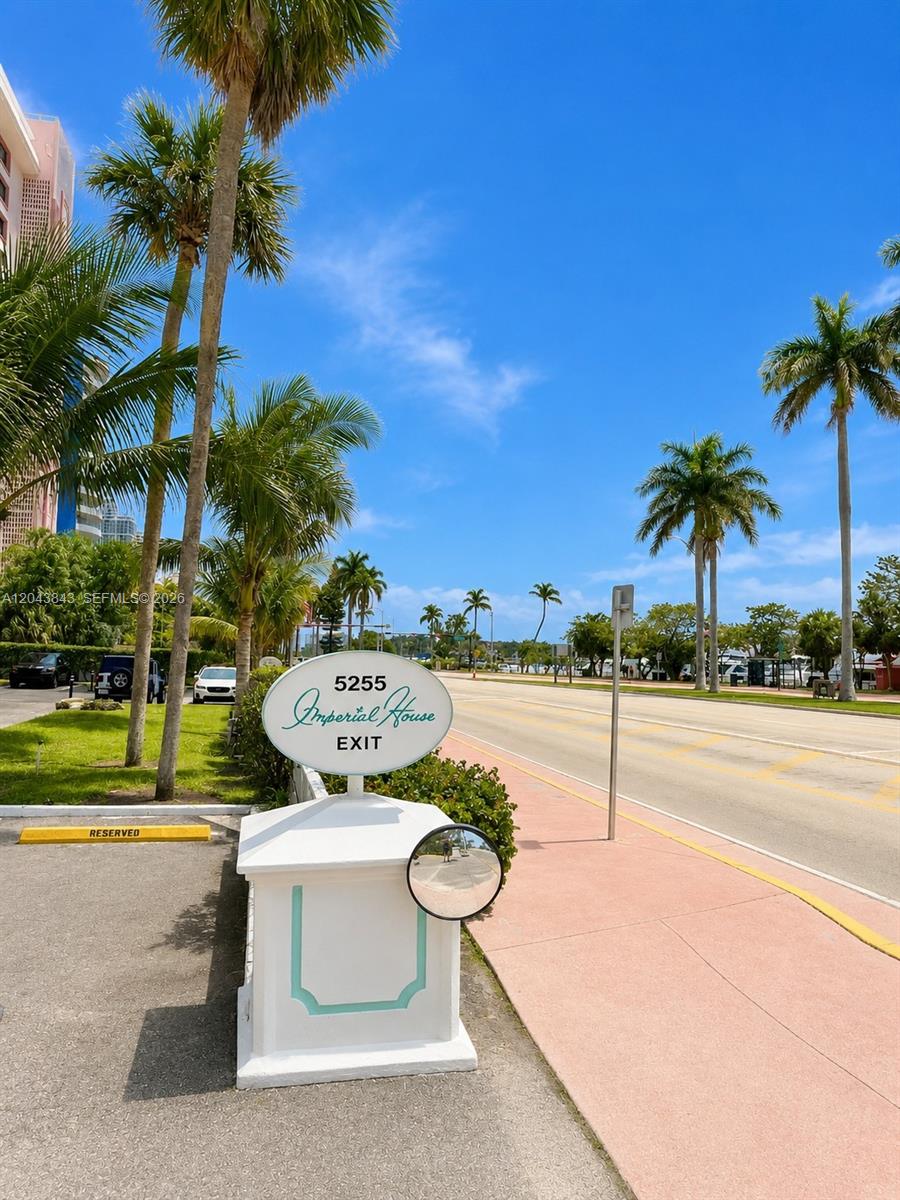 An outdoor view shows a white exit sign for Imperial House beside a palm-lined road — 5255 Collins Ave # 7B, Miami Beach FL 33140, MIAMI BEACH, FL