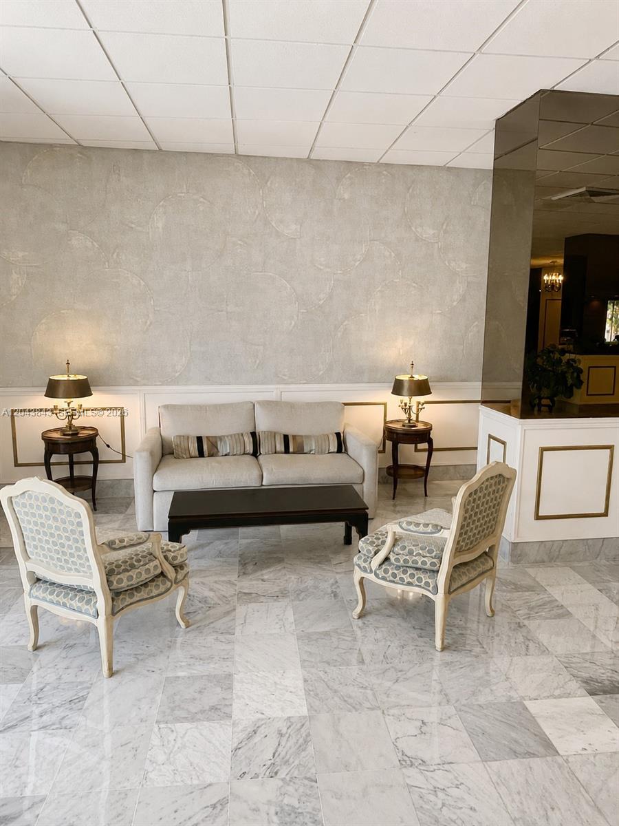 A lobby area features a sofa, two patterned chairs, side tables, and marble flooring — 5255 Collins Ave # 7B, Miami Beach FL 33140, MIAMI BEACH, FL