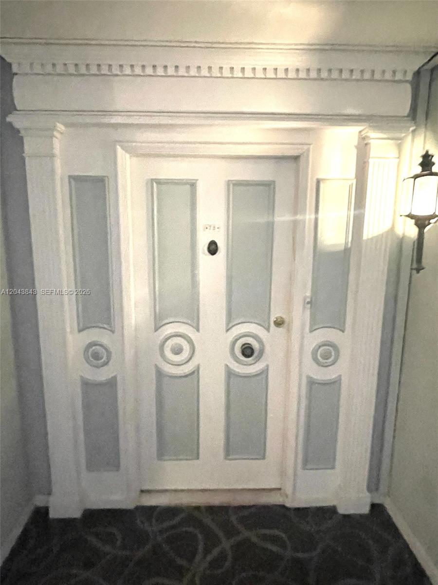 A white double door with decorative circular accents and side panels under a crown molding — 5255 Collins Ave # 7B, Miami Beach FL 33140, MIAMI BEACH, FL