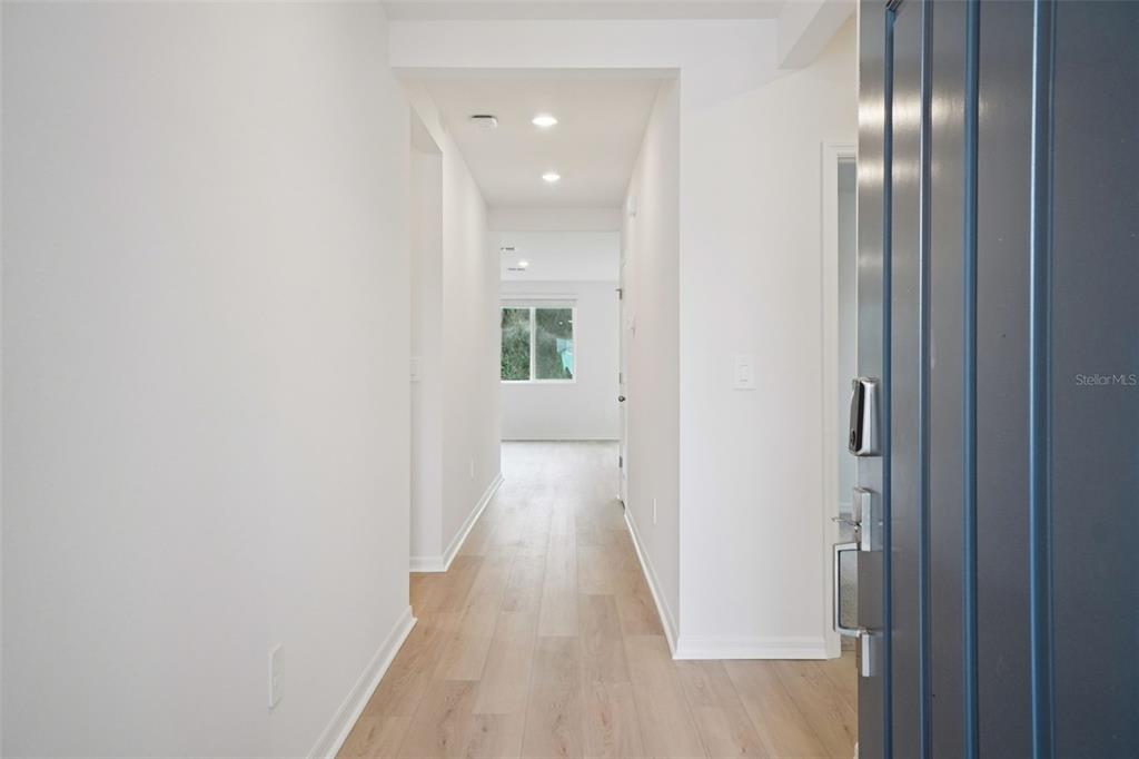 A view from an open doorway looking down a hallway with light wood-look flooring — 7186 RAY CREEK DRIVE, BROOKSVILLE, FL