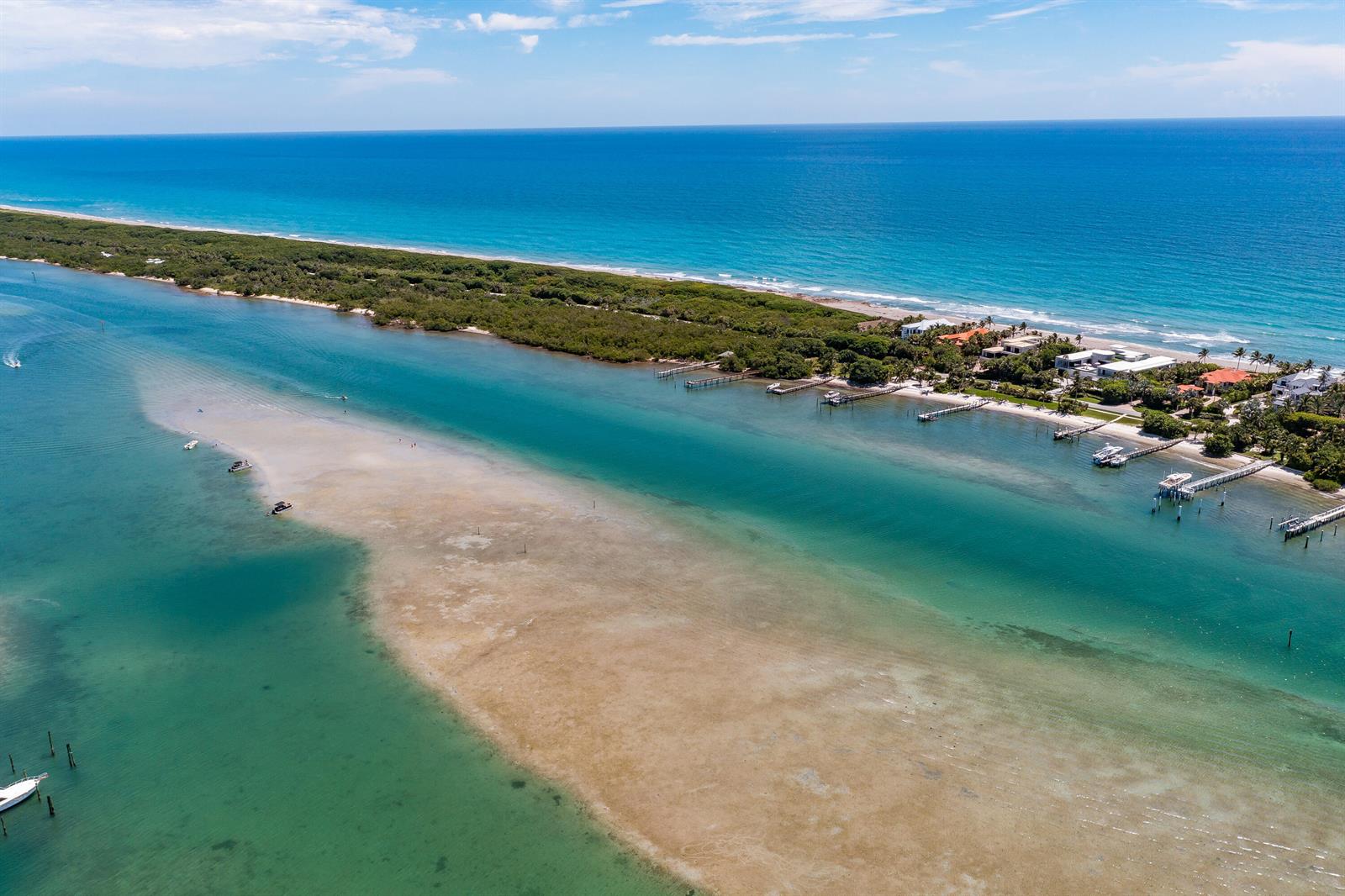 An aerial view shows a coastal waterway with a sandbar, private docks, and oceanfront homes — 100 Intracoastal Place # 205, Jupiter FL 33469, JUPITER, FL