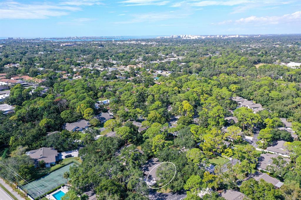 An aerial view shows a residential neighborhood with many trees and a circled house — 4799 OAK FOREST DRIVE W UNIT 43, SARASOTA, FL