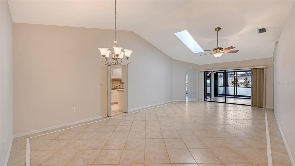 A living and dining area with tile floors, a vaulted ceiling, and a sliding glass door — 4799 OAK FOREST DRIVE W UNIT 43, SARASOTA, FL