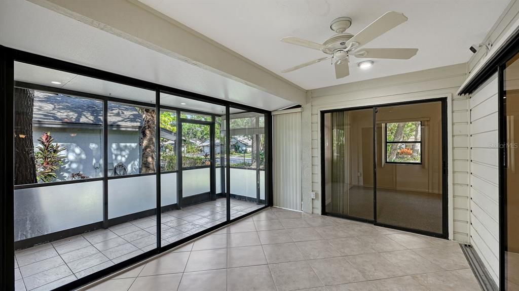 A tiled sunroom features a ceiling fan, sliding glass doors, and screened-in exterior walls — 4799 OAK FOREST DRIVE W UNIT 43, SARASOTA, FL
