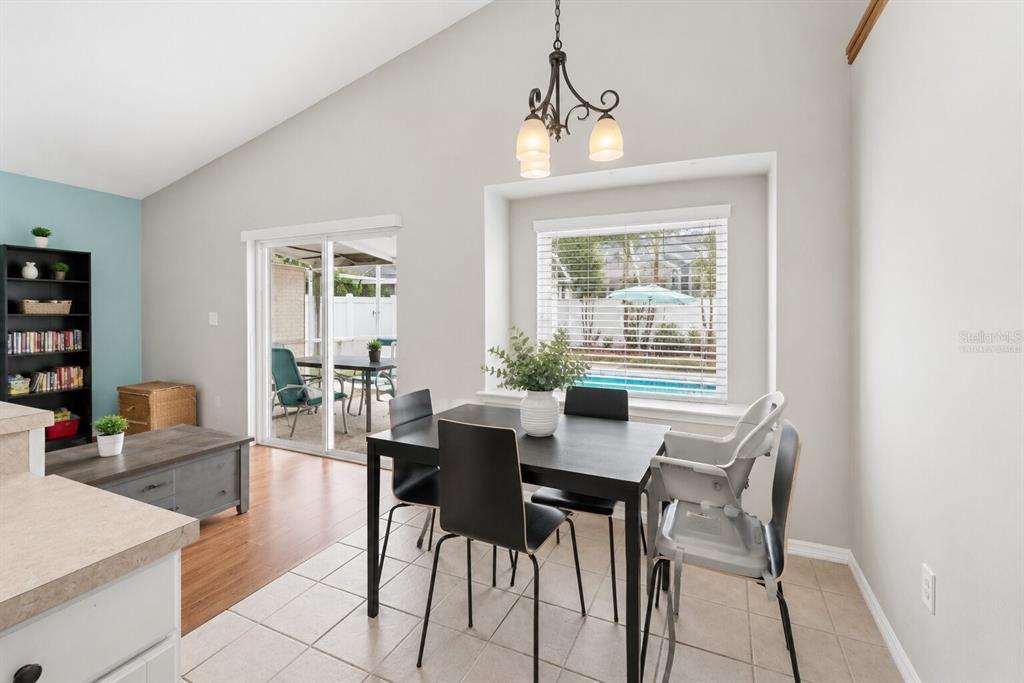 A dining area with a black table, chairs, high chair, and sliding doors to a pool — 22741 RODERICK DRIVE, LAND O LAKES, FL