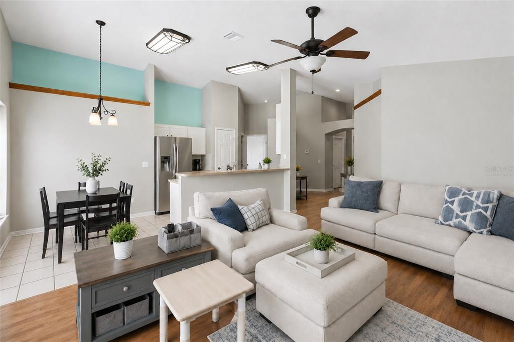 An open-concept living and dining area features light walls, wood-look flooring, and a kitchen island — 22741 RODERICK DRIVE, LAND O LAKES, FL