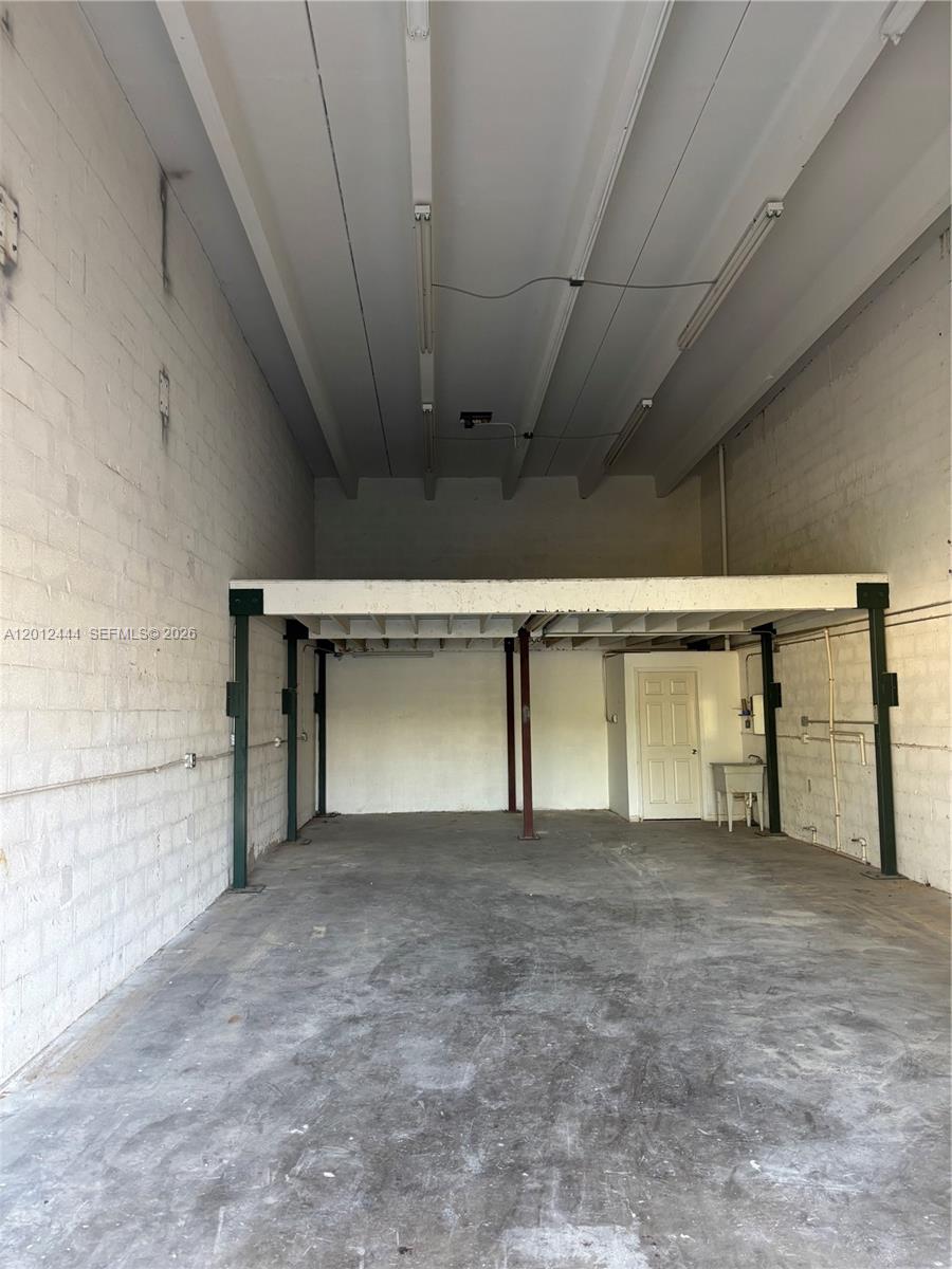 An industrial warehouse space features a concrete floor, white block walls, and a mezzanine level — 14305 SW 142nd St, Miami FL 33186, MIAMI, FL