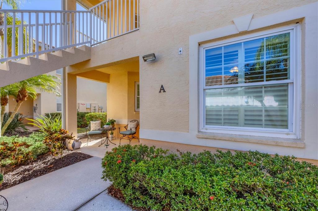 A ground-level apartment entrance features a small patio, a window, and an exterior staircase — 4213 VICENZA DRIVE UNIT A2, VENICE, FL