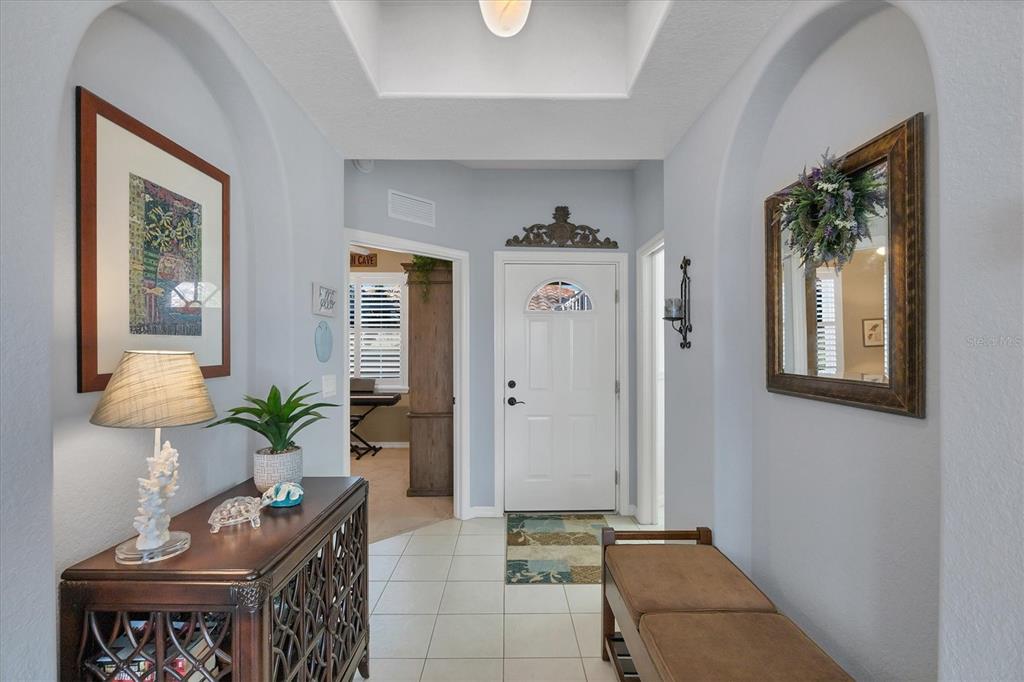 An entryway features a white front door, arched alcoves, tiled flooring, and a wooden console table — 4213 VICENZA DRIVE UNIT A2, VENICE, FL