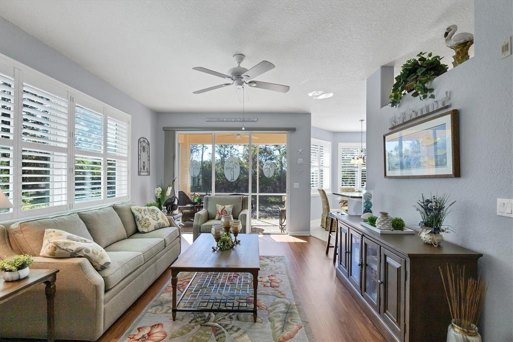A living room features a sofa, coffee table, wood flooring, and a sliding glass door — 4213 VICENZA DRIVE UNIT A2, VENICE, FL