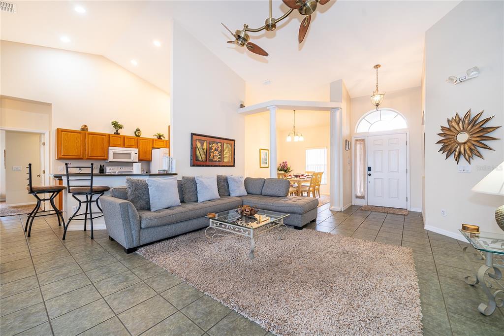 A living room with a gray sectional sofa, tiled floors, and an open kitchen area — 569 BURFORD CIRCLE, DAVENPORT, FL
